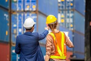 vista trasera del equipo de ingenieros y trabajadores revisando la caja de contenedores del concepto de carga, logística y trabajo en equipo foto