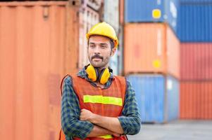 Portrait of Engineer man in hard hat and safety vest, worker with protective headphones at construction site photo