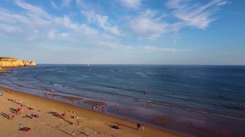 vista aérea de drones de personas en la playa durante una hermosa puesta de sol. increíbles colores vibrantes. algarve, portugal. aguas claras vacaciones y vacaciones. viajes y aventuras. vida nómada.