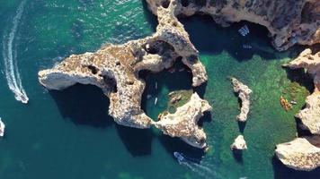 luchtfoto drone shot van kajaks en boten die rond de magische kalkstenen kliffen van ponta da piedade varen. het verkennen van grotten en tunnels van Lagos, Algarve, ten zuiden van Portugal. reizen en avontuur. nomaden leven. video