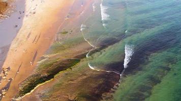 increíble vista aérea escénica de drones de la playa y el océano con olas tranquilas durante una puesta de sol con colores vibrantes. algarve, portugal. aguas claras vacaciones y vacaciones. antecedentes. playa con rocas. video