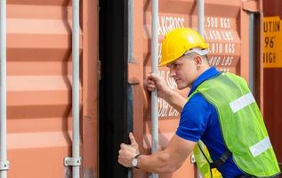 Factory worker man in hardhat and safety vest checking containers box from cargo photo