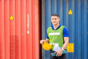 Engineer, worker man holding hard hat at cargo containers photo