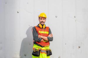 Cheerful engineer man in hard hat smiling with arms crossed and looking at camera photo