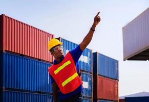 Worker man in hardhat and safety vest point to the sky, Foreman control loading containers box from cargo photo