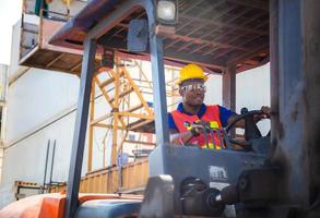 Happy worker man in hardhat and safety vest driving container stackers for control loading containers box from cargo photo