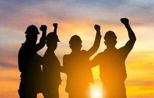 Silhouette of engineer and worker team with clipping path joining hands and celebration with sunset background, Success and Teamwork Concepts photo
