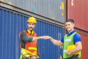 Engineer and worker making a fist bump with blurred containers cargo background, Business success and teamwork concept. photo
