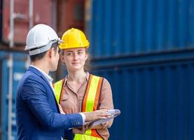 Engineer and foreman worker team in hardhat and safety vest checking containers box from cargo, Teamwork concepts photo