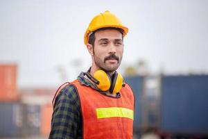 Engineer man in hardhat and safety vest, worker with protective headphones at construction site photo