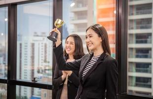 mujer de negocios con trofeo de premio en la sala de reuniones, concepto de equipo de felicidad de éxito de celebración foto