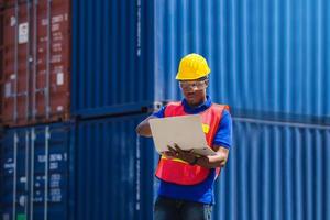 Worker man in hardhat with clipping path and safety vest holding laptop, Foreman control loading containers box from cargo photo