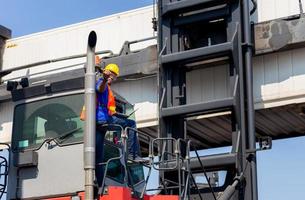 Worker man in hardhat and safety vest holding laptop standing on container stackers control loading containers box from cargo photo