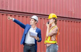 Engineer and worker team checking containers box from cargo, Woman foreman in hardhat and safety vest talks on two-way radio photo