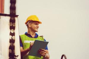 Engineer man in hard hat and safety vest standing on container stackers control loading containers box from cargo photo