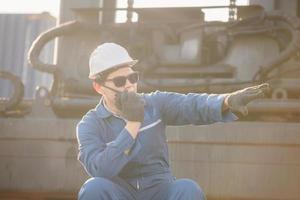 Foreman in hardhat and safety vest talks on two-way radio control loading containers box from cargo photo