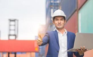 Cheerful engineer man holding laptop with giving thumbs up as sign of success photo