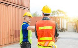 Engineer and foreman worker team checking containers box from cargo with blurred background, Teamwork concept photo