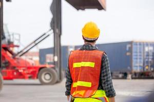 Engineer man in hardhat and safety vest control loading containers box from cargo, Logistic concept photo