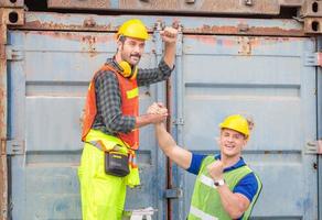 Engineer and worker soul brother handshake, thumb clasp handshake or homie handshake with blurred containers cargo background, Success and Teamwork concept photo