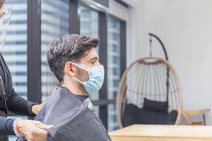 Young man getting haircut by hairdresser, Barber using scissors and comb, New normal concepts photo