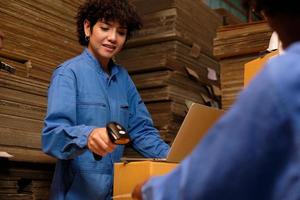 Two safety uniform female workers and colleagues use bar code scanner to check shipment orders stock at parcels warehouse, paper manufacture factory for packing industry, logistic transport service. photo