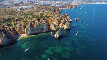 ripresa aerea di kayak e barche che passano intorno alle magiche scogliere calcaree di ponta da piedade. esplorare grotte e tunnel di lagos, algarve, a sud del portogallo. viaggi e avventure. vita nomade. video