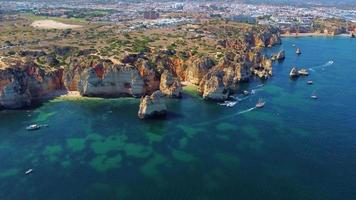 luchtfoto drone shot van kajaks en boten die rond de magische kalkstenen kliffen van ponta da piedade varen. het verkennen van grotten en tunnels van Lagos, Algarve, ten zuiden van Portugal. reizen en avontuur. nomaden leven. video