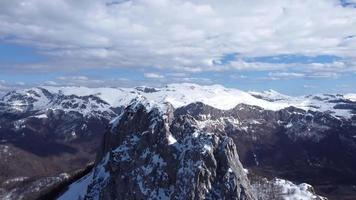 vista aérea do drone do pico da montanha de difícil acesso para alpinistas durante um dia ensolarado de inverno. alpinismo e alpinistas. céu azul e cores vibrantes brancas. tiro cinematográfico. mais aventura na vida.