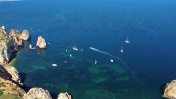 drönare från luften av kajaker och båtar som passerar runt magiska kalkstensklippor från Ponta da Piedade. utforska grottor och tunnlar i lagos, algarve, söder om portugal. resor och äventyr. nomadliv. video