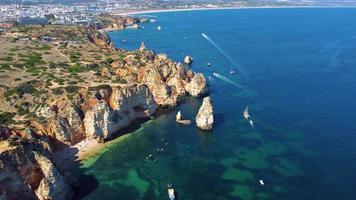 Aerial drone shot of kayaks and boats passing around magical Ponta da Piedade limestone cliffs. Exploring caves and tunnels of Lagos, Algarve, South of Portugal. Travel and adventure. Nomad life.