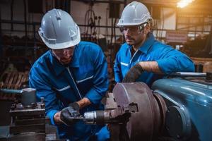 ingeniería industrial con control uniforme de seguridad que opera la máquina rectificadora de torno que trabaja en la fábrica de la industria. foto