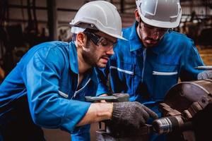 ingeniería industrial con control uniforme de seguridad que opera la máquina rectificadora de torno que trabaja en la fábrica de la industria. foto