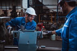 Industry engineering wearing safety uniform control operating computer controlled lathe grinding machine working in industry factory. photo