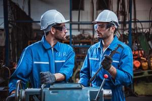 ingeniería industrial con control uniforme de seguridad que opera la máquina rectificadora de torno controlada por computadora que trabaja en la fábrica de la industria. foto