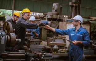 ingeniería industrial con control uniforme de seguridad que opera la máquina rectificadora de torno controlada por computadora que trabaja en la fábrica de la industria. foto