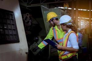 ingeniería industrial con control uniforme de seguridad que opera la máquina rectificadora de torno controlada por computadora que trabaja en la fábrica de la industria. foto