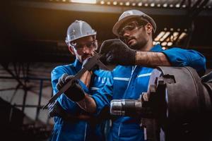 ingeniería industrial con control uniforme de seguridad que opera la máquina rectificadora de torno controlada por computadora que trabaja en la fábrica de la industria. foto