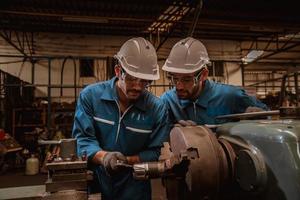 ingeniería industrial con control uniforme de seguridad que opera la máquina rectificadora de torno controlada por computadora que trabaja en la fábrica de la industria. foto