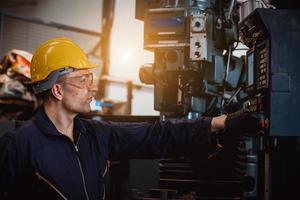 Industry engineering wearing safety uniform control operating computer controlled lathe grinding machine working in industry factory. photo