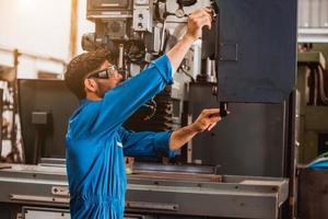 ingeniería industrial con control uniforme de seguridad que opera la máquina rectificadora de torno controlada por computadora que trabaja en la fábrica de la industria. foto