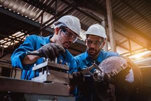 ingeniería industrial con control uniforme de seguridad que opera la máquina rectificadora de torno que trabaja en la fábrica de la industria. foto