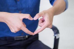 Close-up of young man making heart shape with fingers photo