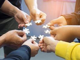 Many young people hands holding jigsaw puzzle pieces in circle photo