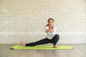 Latin woman practicing yoga on mat photo