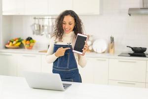 Latin woman shooting video and cooking at the kitchen photo