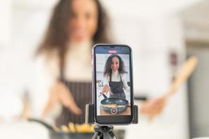 mujer latina grabando video y cocinando en la cocina foto