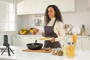 Latin woman shooting video and cooking at the kitchen photo