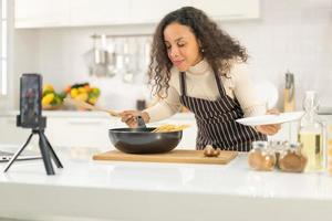 Latin woman shooting video and cooking at the kitchen photo