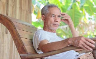 Asian senior man on rocking chair relaxing retired life photo